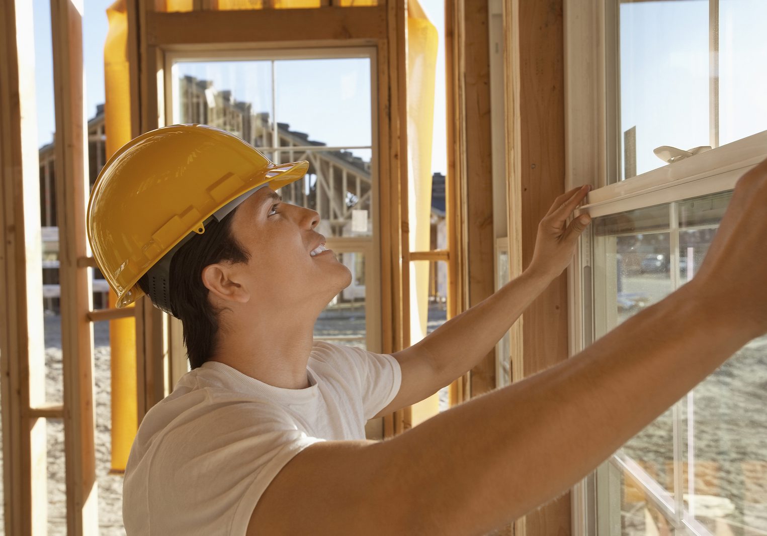 Side view of a construction worker in hardhat working on building window